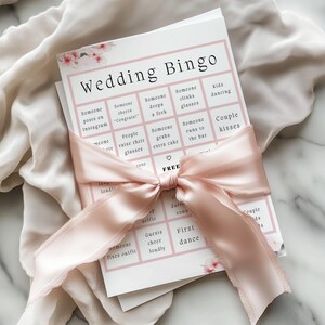 Wedding bingo printable game card with pink ribbon and cherry blossom design, elegant wedding reception game for guests