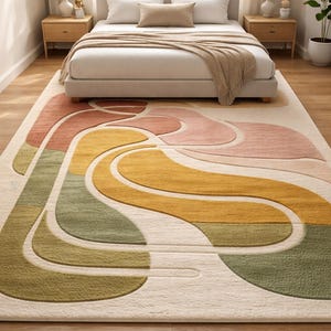 May include: A large, rectangular area rug with an abstract design in a bedroom setting. The rug features a cream-colored background with flowing shapes in shades of green, yellow, pink, and orange. The rug is placed in front of a bed.