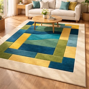 May include: A rectangular area rug with a geometric design in shades of blue, green, and yellow. The rug has a cream-colored border and is placed in a living room setting with a sofa and coffee table.
