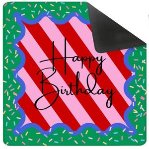May include: A rectangular mat with a green background scattered with colorful sprinkles. The center features a red and pink striped design with the words "Happy Birthday" in black script. A blue wavy border frames the striped area.