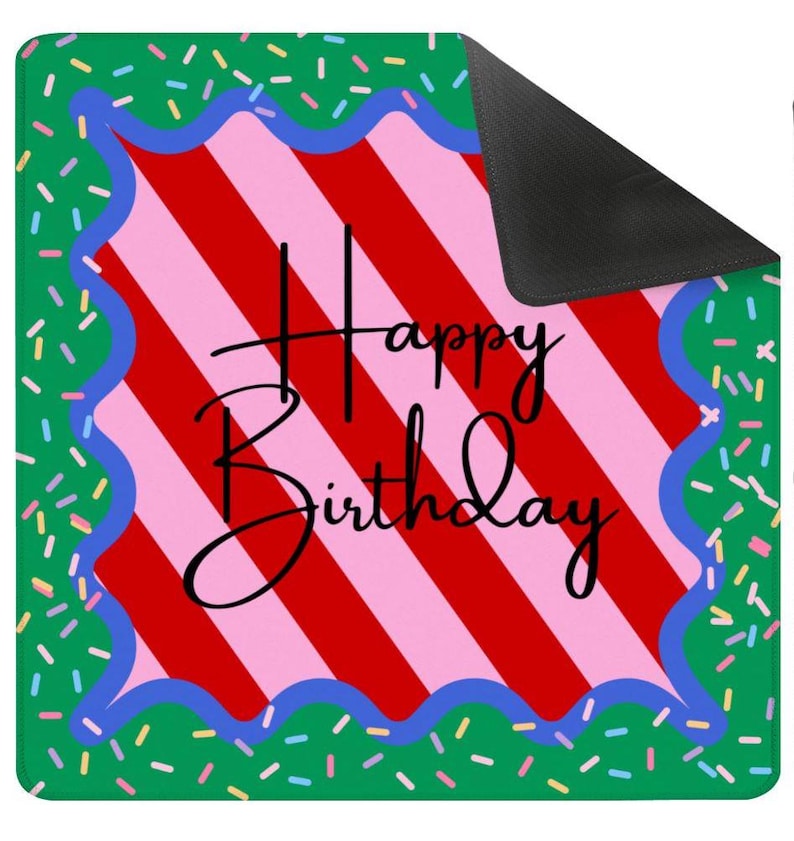 May include: A rectangular mat with a green background scattered with colorful sprinkles. The center features a red and pink striped design with the words "Happy Birthday" in black script. A blue wavy border frames the striped area.