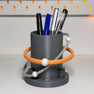 Portapenne a forma di acceleratore di particelle, scultura da scrivania ad anello orbitante, organizer per articoli di fisica stampato in 3D.