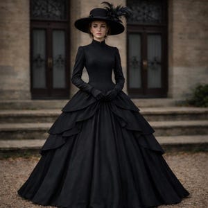 May include: A floor-length black gown with long sleeves, a high neckline, and a multi-layered skirt. The ensemble includes matching black gloves and a wide-brimmed black hat adorned with dark feathers, creating a cohesive monochromatic appearance.