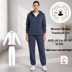 以下が含まれることがあります： ネイビーブルーのモーダル女性用トラックスーツセット。フード付きジップアップジャケットとマッチするパンツが含まれています。画像には、衣装の線画と「Women Modal Tracksuit Set」のテキストも表示されています。サイズはUS 2～30、XS～4XLです。