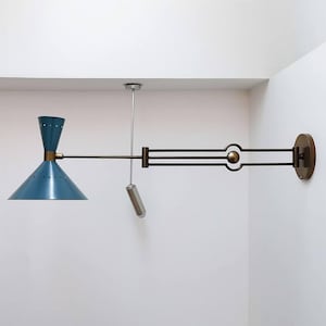 Puede incluir: Una lámpara de pared azul y latón con una pantalla cónica y un brazo ajustable. La lámpara tiene una cadena de tracción y una base circular. El diseño es moderno de mediados de siglo.