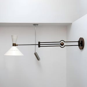 May include: A white and brass wall-mounted lamp with a conical shade and a pivoting arm. The lamp has a cylindrical pull chain and a circular base. The shade has small perforations around the bottom.