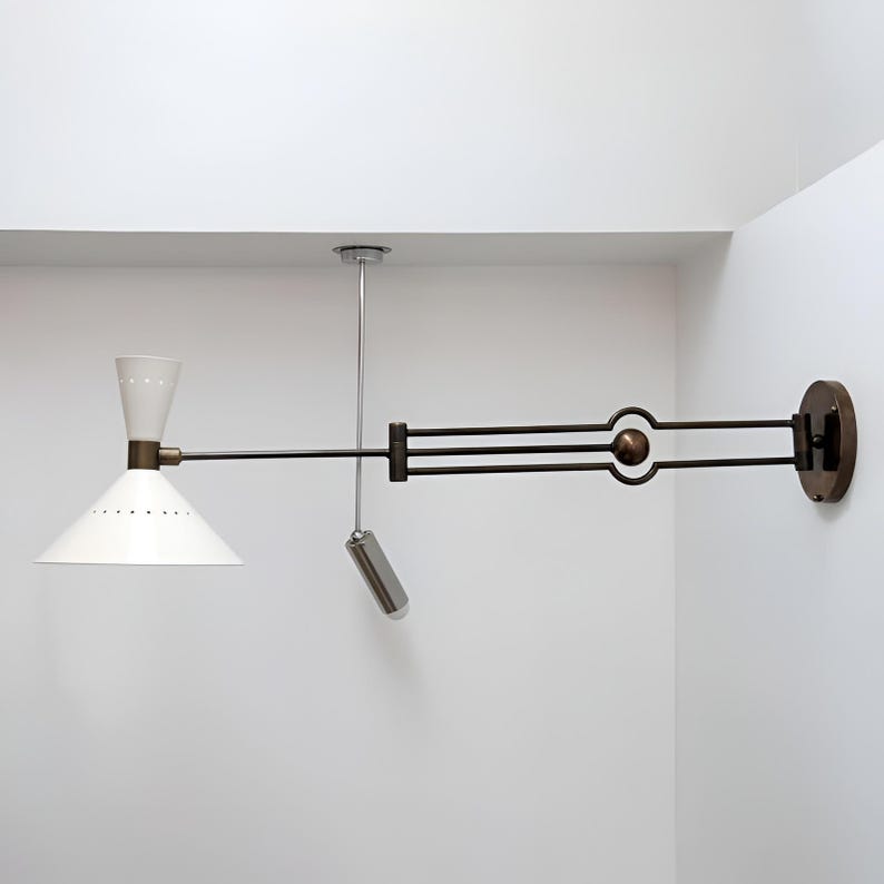 May include: A white and brass wall-mounted lamp with a conical shade and a pivoting arm. The lamp has a cylindrical pull chain and a circular base. The shade has small perforations around the bottom.