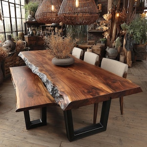 May include: A large live edge wooden dining table and matching bench featuring a rich brown grain and natural bark edges. The set is supported by sturdy black metal U-shaped legs. A round grey bowl with dried foliage sits on the table surface.
