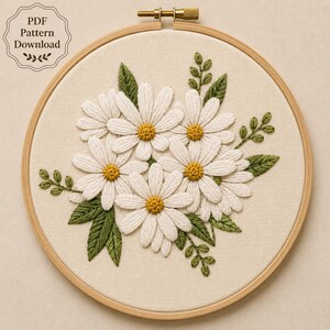 May include: A circular wooden embroidery hoop containing a fabric panel with a hand-stitched design of white daisies with yellow centers and green leaves. The text "PDF Pattern Download" is printed in the upper left corner of the image.