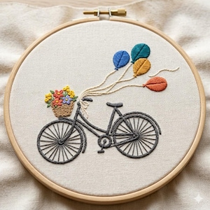 Könnte beinhalten: Gesticktes Kunstwerk in einem Holzreifen. Das Design zeigt ein graues Fahrrad mit einem Korb voller bunter Blumen und vier ballonförmigen Verzierungen in Blau, Gold und Orange. Der Hintergrund ist ein neutraler Stoff.