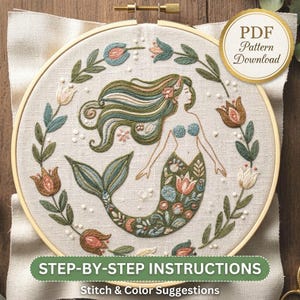 May include: An embroidery hoop containing a fabric panel with a stitched mermaid design surrounded by a floral wreath. The mermaid features long flowing hair and a tail decorated with floral motifs. Text reads PDF Pattern Download and STEP-BY-STEP INSTRUCTIONS Stitch & Colour Suggestions.