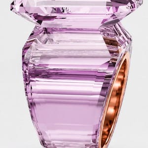 Könnte beinhalten: Ein großer, facettierter, hellvioletter Edelsteinring mit einem markanten Smaragdschliff-Stein auf einem dicken, blockartigen, durchscheinenden lavendelfarbenen Ringband. Die Innenseite des Ringbandes ist mit glattem, poliertem Roségold ausgekleidet.