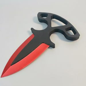 Puede incluir: Una daga negra y roja con un diseño de mango único. La hoja es roja y el mango es negro con una forma distintiva. La daga es probablemente un artículo decorativo o un accesorio.