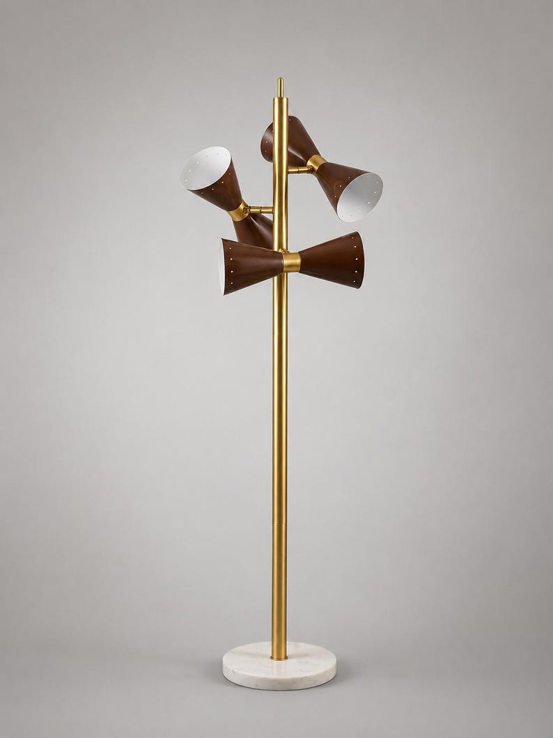 May include: A floor lamp with a central gold-toned metal pole and a circular white marble base. The lamp features three double-ended cone-shaped shades in a dark brown finish with white interiors, attached to the pole with gold-toned metal hardware.