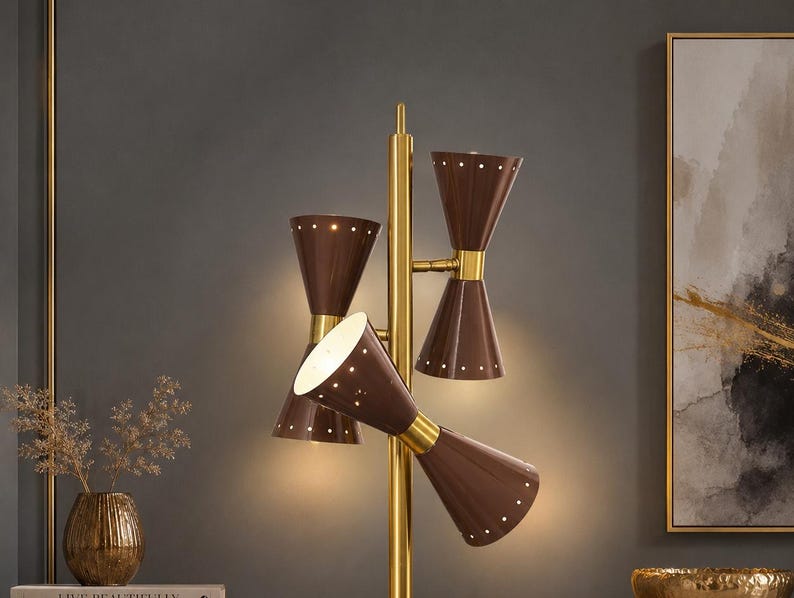 May include: A floor lamp featuring a central gold-toned metal pole with three double-cone shaped shades in a dark brown finish. Each cone shade is accented with a series of small circular perforations along the edges, emitting a warm light.