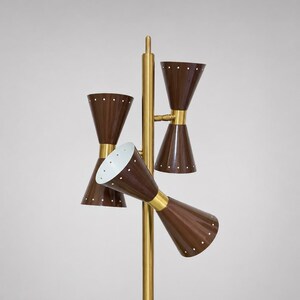May include: A floor lamp featuring a central brass pole with three double-cone shades in a dark brown finish. Each cone is accented with small white dots arranged in a circular pattern. The interior of the shades is white, and the brass hardware connects the shades to the main vertical support structure.