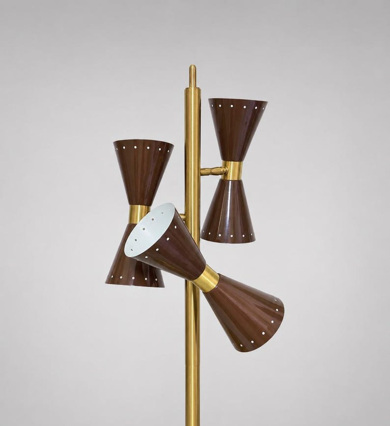 May include: A floor lamp featuring a central brass pole with three double-cone shades in a dark brown finish. Each cone is accented with small white dots arranged in a circular pattern. The interior of the shades is white, and the brass hardware connects the shades to the main vertical support structure.