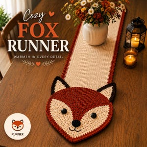 May include: A cozy fox runner with a red, cream, and black color scheme. The runner features a fox face design at one end and is displayed on a wooden table. The text "Cozy Fox Runner" is visible in the image.