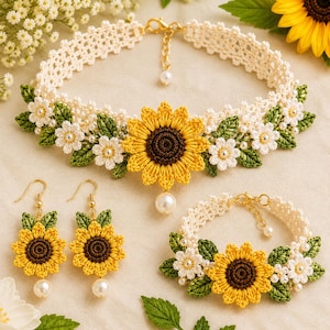 May include: A crochet jewelry set featuring a sunflower design. The set includes a necklace, earrings, and a bracelet. The necklace and bracelet have a cream-colored base with yellow sunflowers, white flowers, and green leaves. The earrings have a sunflower and pearl drop.