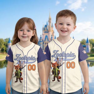 May include: Two children wearing cream-colored baseball jerseys with navy blue sleeves. The jerseys feature the word "Zootopia" in light blue script, the number "00" in orange, and a graphic of Nick Wilde and Judy Hopps.