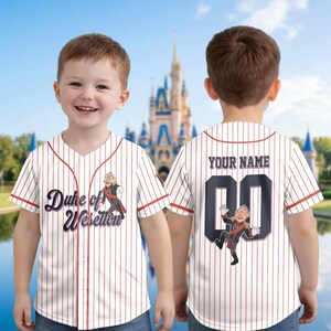 May include: White and red pinstripe baseball jersey with the text "Duke of Weselton" and a cartoon character on the front. The back features the text "YOUR NAME" above a number 00 and another cartoon character.