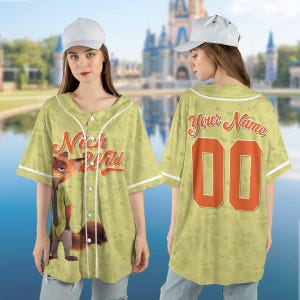 Puede incluir: Una camiseta de b&eacute;isbol verde claro con el texto "Nick & Wild" y un personaje de zorro de dibujos animados en la parte delantera. La parte trasera tiene el texto "Your Name" y el n&uacute;mero "00" en naranja.
