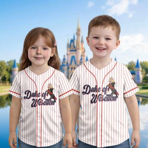 May include: Two children wearing white baseball jerseys with red pinstripes and trim. The jerseys feature the text "Duke of Weselton" and a cartoon image. The background shows a castle.