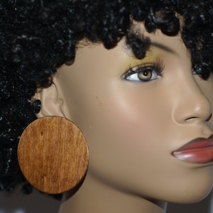 May include: A pair of large, round wooden earrings. The earrings are a rich brown color and have a smooth, polished finish.