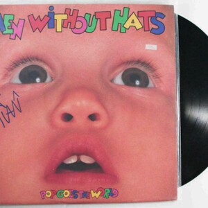 May include: Album cover for "Men Without Hats" featuring a close-up of a baby's face with the band's name in colorful letters. The album title "Pop Goes the World" is at the bottom. A black vinyl record is visible.