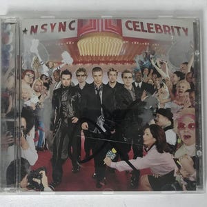 May include: A CD case featuring the *NSYNC album "Celebrity." The cover art shows the band members in black outfits on a red carpet, surrounded by a crowd of people and paparazzi. The album title is displayed in large letters.