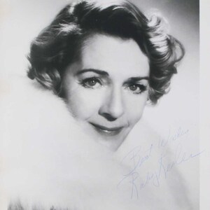 May include: Black and white portrait of a woman with styled hair and a fur collar. The image includes the handwritten text "Best Wishes, Ruby Keeler" in blue ink.