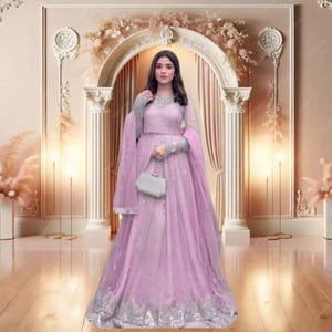 May include: A light purple formal gown with silver embroidery on the sleeves and hem. The gown features a flowing skirt and a matching shawl. A small, silver clutch is held in the hand. The background includes an archway and decorative floral arrangements.