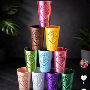 Peut inclure: Une pile de dix gobelets colorés aux couleurs rose, marron, jaune, vert, bleu, rouge, pêche, blanc, violet et sarcelle. Chaque gobelet présente un motif de feuille et le mot "Guiselle".