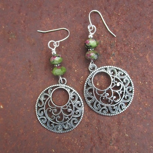 May include: Silver earrings with a filigree design and green and pink gemstone beads.