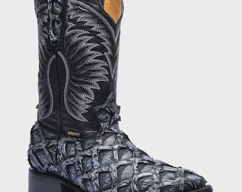 May include: A black leather cowboy boot featuring a textured, grey-toned scale-like pattern on the foot and a tall shaft with intricate silver-grey stitching in a wing-like design, complete with a low block heel and a square toe profile.
