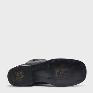 May include: A black leather western boot with a square toe and a stacked heel. The sole features a stamped logo with the letters JP inside a state of Texas outline, surrounded by a repeating star pattern and additional embossed branding.