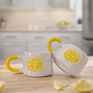 May include: A set of three ceramic mugs with a speckled, cream-colored glaze. Each mug features a different hand-painted floral design in shades of blue, green, and yellow. The mugs have a simple, modern shape.