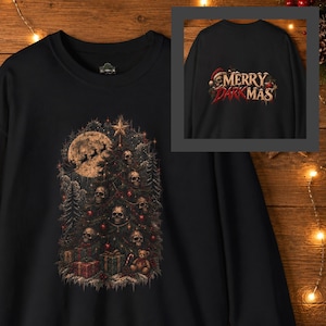 Könnte beinhalten: Ein schwarzes Langarm-Sweatshirt mit einer Grafik eines Weihnachtsbaums, der mit Totenköpfen, einem Stern und Kugeln geschmückt ist. Unter dem Baum liegen Geschenke. Ein kleiner Ausschnitt zeigt die Rückseite mit dem Text MERRY DARK MAS.