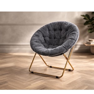 May include: A gray, plush, round accent chair with a tufted seat. The chair has a gold-colored metal frame and a folding design. The chair is designed for indoor use and is placed on a wooden floor.
