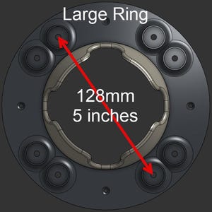May include: A dark gray circular component labeled Large Ring with a central wavy cutout and eight small circular mounting points. A red arrow indicates a diameter measurement of 128mm or 5 inches across the object on a dark background.