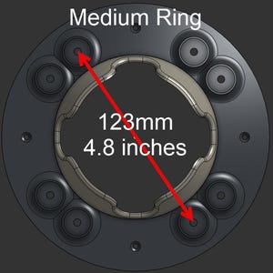 May include: A circular dark gray Medium Ring component featuring a central opening with a wavy edge and eight small circular mounting points. A red arrow indicates a diameter measurement of 123mm or 4.8 inches across the center of the object.