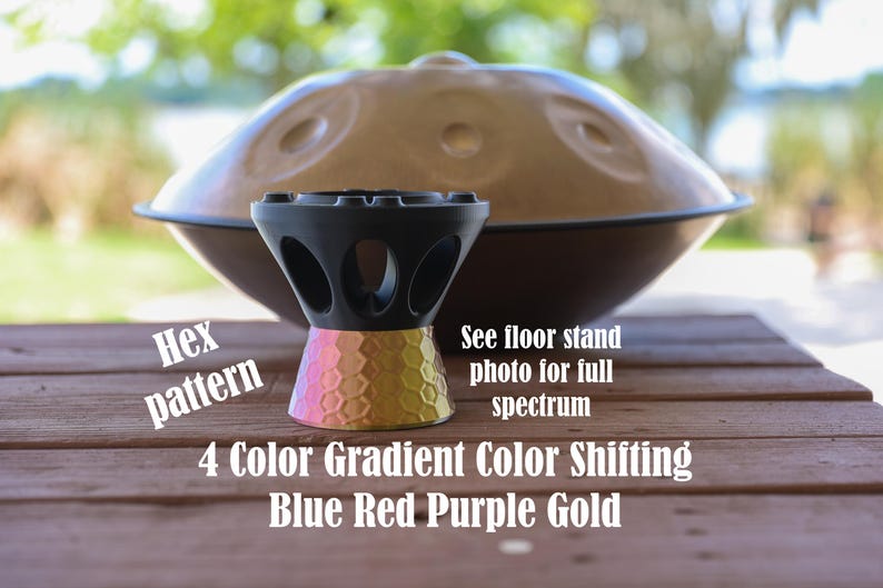 May include: A black handpan stand with a hexagonal pattern base featuring a 4 color gradient of blue, red, purple, and gold. Text on the image reads: Hex pattern, See floor stand photo for full spectrum, 4 Color Gradient Color Shifting Blue Red Purple Gold.