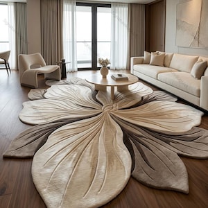Könnte beinhalten: Ein großer, blütenförmiger Teppich in Beige- und Brauntönen dominiert den Raum. Das Design des Teppichs ähnelt einer stilisierten Blume mit detaillierten, blütenblattartigen Abschnitten. Der Raum verfügt außerdem über ein beiges Sofa, einen runden Couchtisch und einen modernen Sessel.