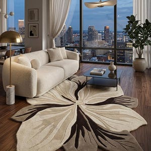 May include: A large, petal-shaped area rug featuring a central floral design in shades of cream, beige, and dark brown. The rug has a textured, tufted surface with organic, curved lines radiating from the center, mimicking the appearance of a flower.