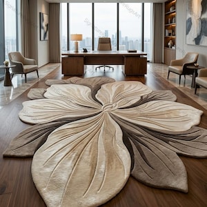 May include: A large, floor-covering rug shaped like a stylized flower with multiple overlapping petals. The rug features a gradient color palette of cream, beige, and dark brown, with carved, recessed lines that define the petal shapes.