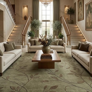 May include: A large area rug featuring a sage green background with a raised, dark brown vine and leaf pattern. The rug is positioned in a grand room with three cream-coloured sofas, a wooden coffee table, and a crystal chandelier hanging above.