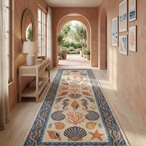 Puede incluir: Una alfombra pasillera rectangular larga con fondo color crema y un patrón repetitivo de conchas, estrellas de mar, caballitos de mar y corales en tonos azules, naranjas y rosas. La alfombra tiene un borde decorativo con motivos de olas.