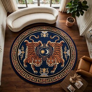 Könnte beinhalten: Ein großer runder Teppich mit tiefblauem Hintergrund und zwei symmetrischen, orange-schwarzen Tigern, die einander gegenüberstehen. In der Mitte befindet sich ein Sonnen- und Mondsymbol, umrahmt von einer goldenen Mäanderbordüre.