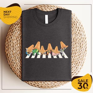 a gray t-shirt with a graphic design of cartoon characters crossing a crosswalk.