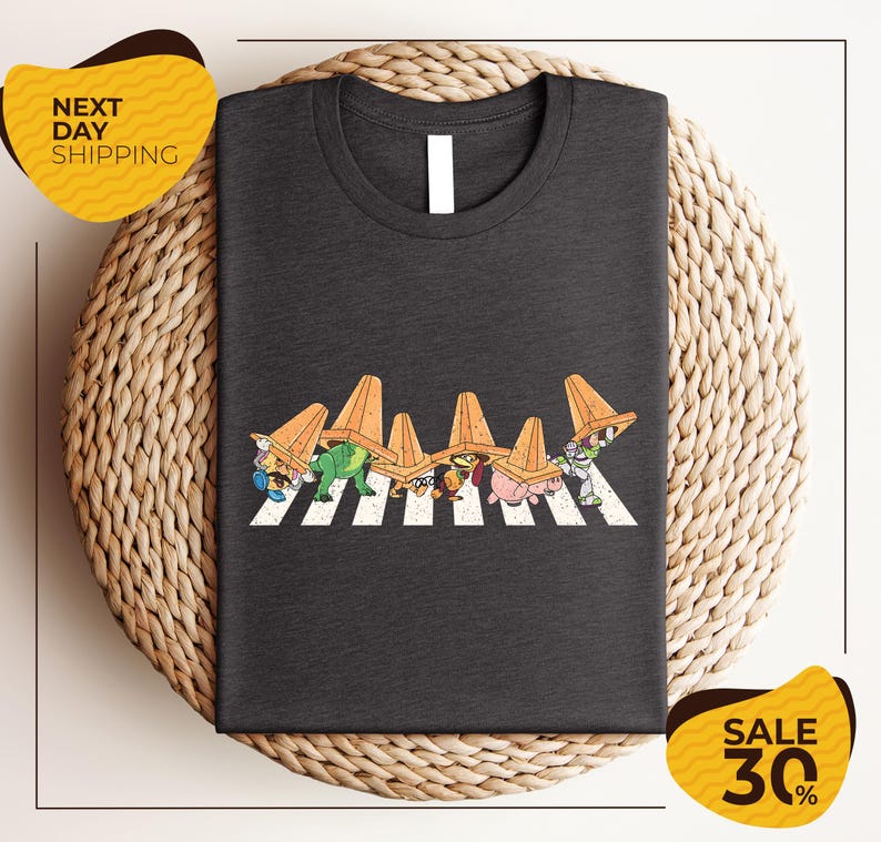 a gray t-shirt with a graphic design of cartoon characters crossing a crosswalk.